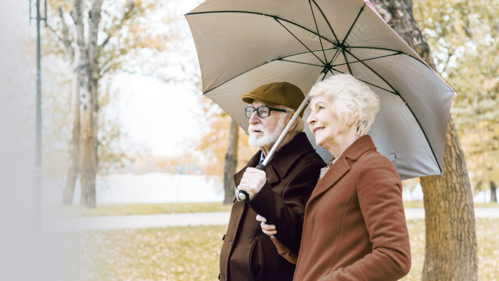 older man and woman walking with umbrella